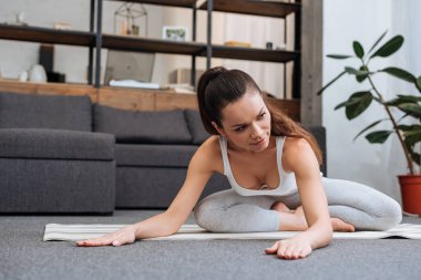 Genç kadının evde oturma odasında germe egzersiz yaparak seçici odak