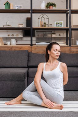 ardha matsyendrasana evde oturma odasında pratik kadın
