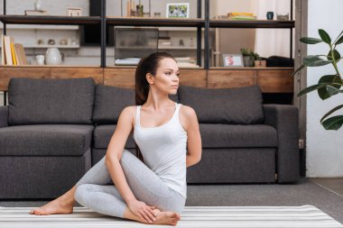 ardha matsyendrasana evde oturma odasında pratik kadın