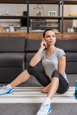 Fitness mindere oturmuş ve Smartphone'da evde konuşmak çekici sporcumuz