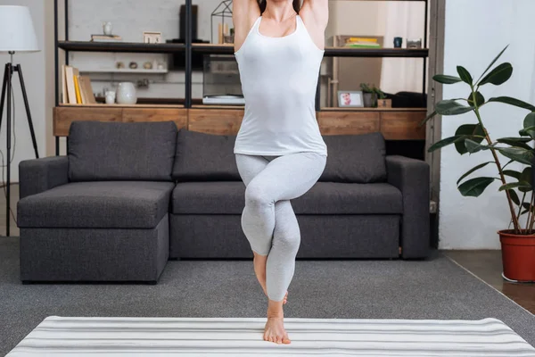 cropped view of woman practicing eagle pose at home in living room