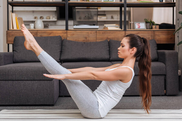 woman practicing boat pose at home in living room