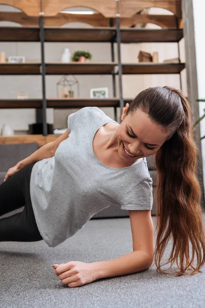 Lachende Sportvrouw Doen Zijkant Plank Oefening Thuis — Stockfoto
