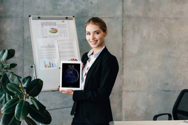 Güzel iş kadını gösteren ipad ekran gülümseyen ve Office kamera bakıyor