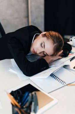 selective focus of exhausted businesswoman sleeping at work-table clipart