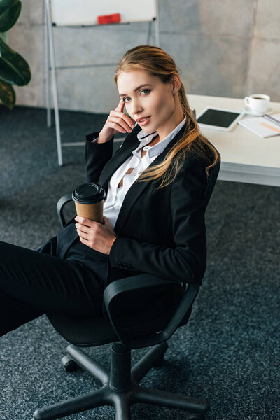 Selected focus of businesswoman sitting in chair with disposal cup of coffee