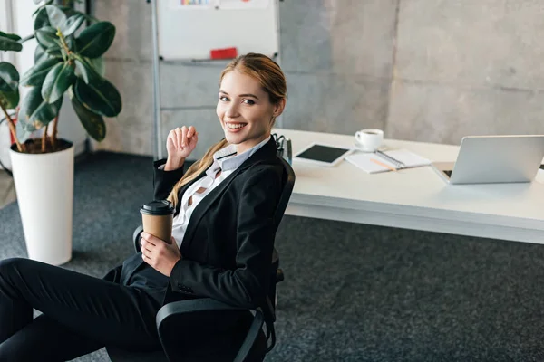 Lächelnde Junge Geschäftsfrau Sitzt Mit Entsorgungstasse Kaffee Auf Stuhl — Stockfoto