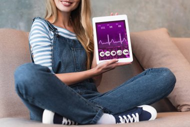 kanepe ve dijital Tablet gösteren ekran üzerinde oturan kadın kırpılmış görünümünü