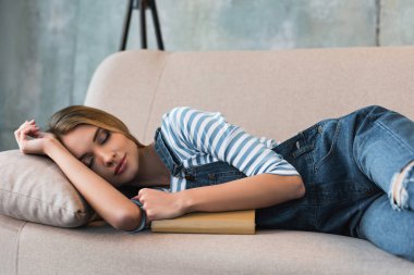 selective focus of beautiful woman sleeping on pink sofa with book