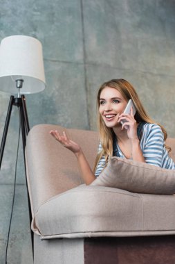 smartphone üzerinde konuşmak ve pembe koltukta yalan mutlu kadın