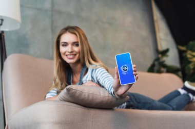 seçici odak pembe Divan güzel kızın elinde shazam app ile Smartphone