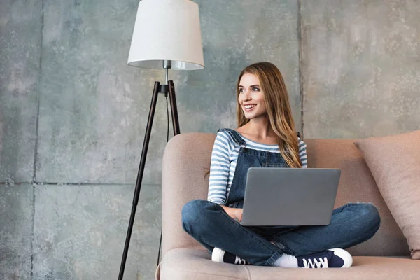 Schöne Frau Lächelt Und Sitzt Auf Sofa Mit Laptop — Stockfoto