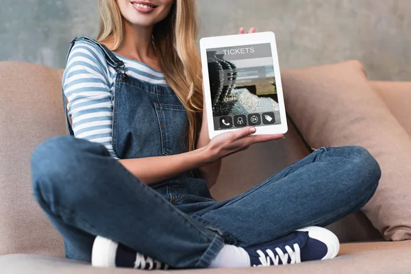 Genç kız kanepe ve bilet ile gösteren ekran üzerinde oturan kırpılmış görünümünü