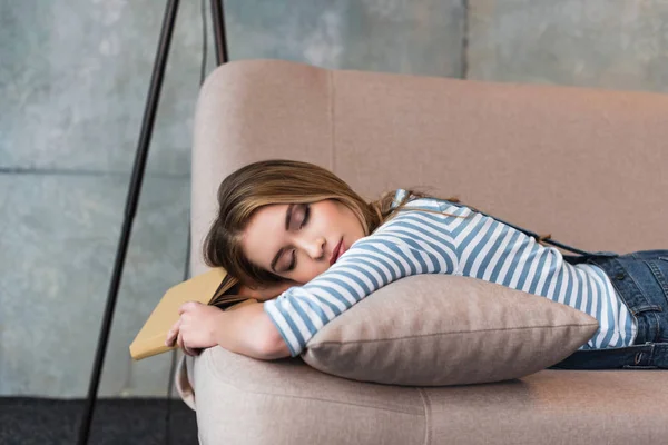 elinde kitapla pembe kanepede uyuyan genç güzel kadın