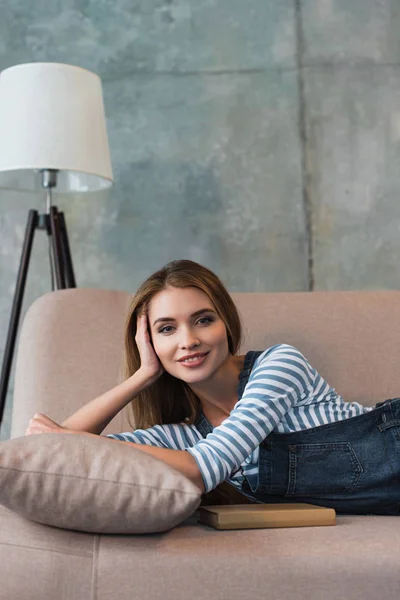 Mooie Vrouw Glimlachend Liggend Roze Sofa Met Boek — Stockfoto