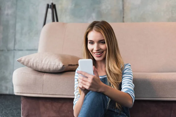 Jovem Mulher Sorrindo Usando Smartphone Sentado Perto Sofá Rosa — Fotografia de Stock