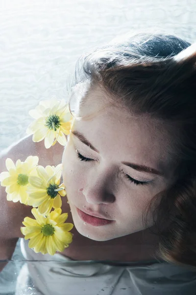 美しい女性が黄色い花を持つ水中ポーズのクローズ アップ — ストック写真
