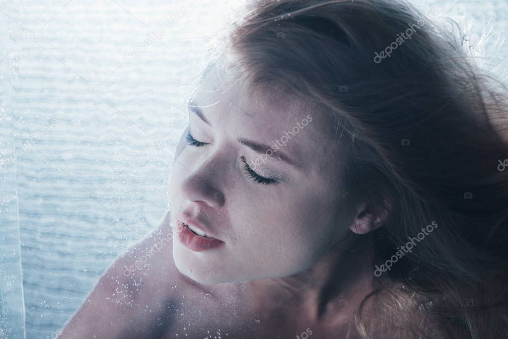 close up of young girl posing underwater with closed eyes