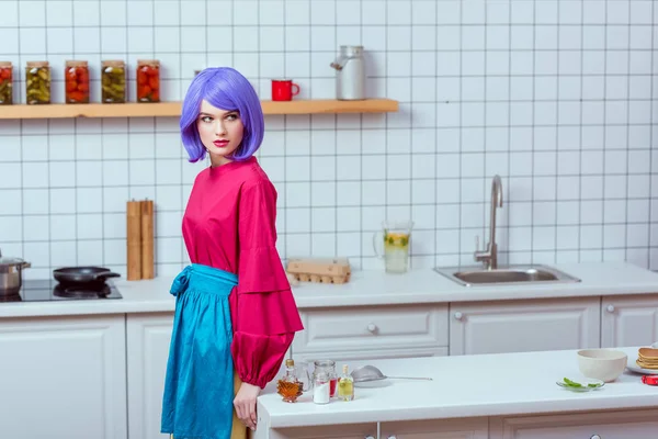 选择焦点美丽的家庭主妇与紫色的头发和五颜六色的衣服摆在厨房与复制空间 — 图库照片