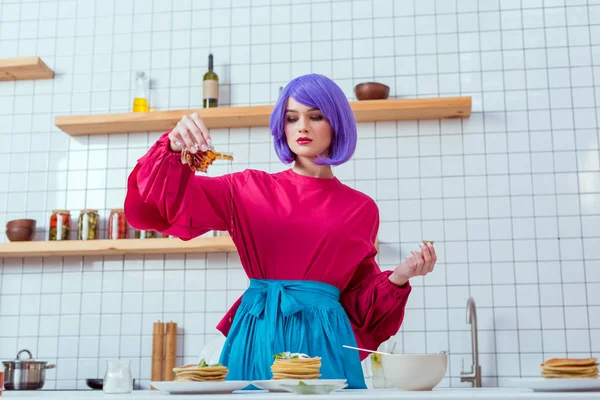 Focused Housewife Purple Hair Colorful Clothes Pouring Syrup Pancakes Kitchen — Stock Photo, Image