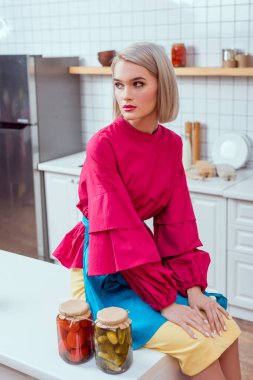 kavanoz turşu sebze mutfak ile mutfak tezgahı üzerinde oturan güzel moda ev kadını 