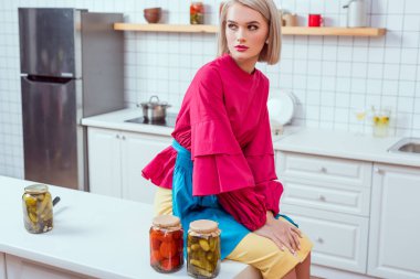 kavanoz turşu sebze mutfak ile mutfak tezgahı üzerinde oturan güzel moda ev kadını 