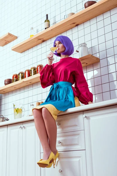 家庭主妇紫色的头发和五颜六色的衣服坐在厨房柜台上 喝着自制的柠檬水 — 图库照片