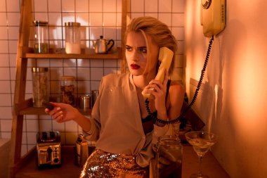 güzel kadın turuncu ışık ile mutfakta retro telefon üzerinde söz karıştı