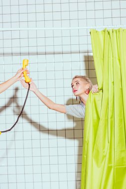 beautiful woman taking yellow retro telephone handset in shower with green curtain clipart