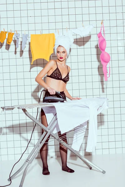 banyo giysilerle Ütü ve uzağa bakarak kafa havluya ile güzel ev kadını