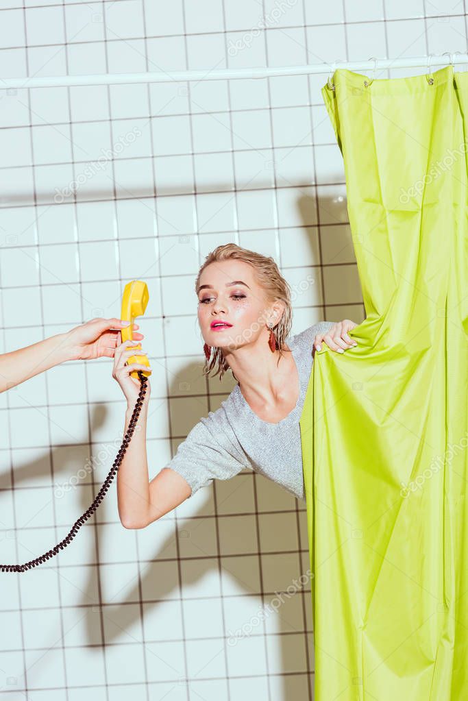 beautiful woman taking yellow retro telephone handset in shower with green curtain
