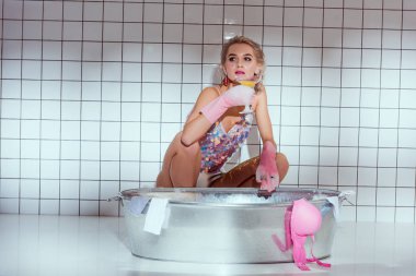 Lastik eldiven kokteyl cam banyo giysileri yıkarken tutan genç ev hanımı
