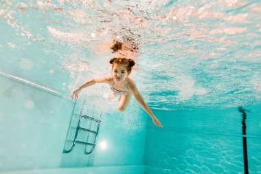 adorable kid swimming underwater in clear water in swimming pool  clipart