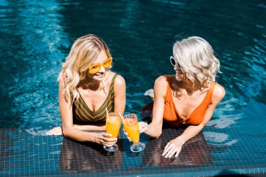 beautiful pin up girls relaxing in swimming pool with cocktails clipart