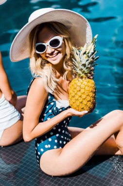 Mayo, güneş gözlüğü ve şapka ananas yakınındaki Yüzme Havuzu ile poz güzel mutlu kadın