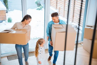 neşeli annesi ve babası yeni evinde kutuları tutarak bakarak çocuğun