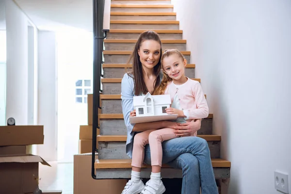 Femme Gaie Assise Avec Fille Dans Les Escaliers Tenant Modèle — Photo