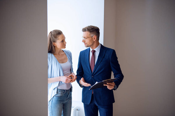 handsome broker looking at beautiful woman while standing in room 