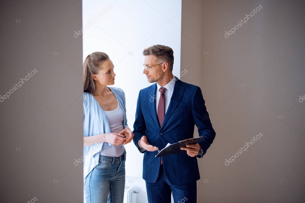 handsome broker looking at beautiful woman while standing in room 