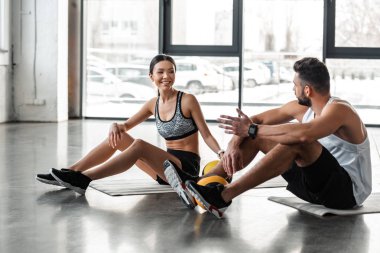 yoga paspaslar üzerine oturan ve spor salonunda konuşurken spor giyim atletik genç çift