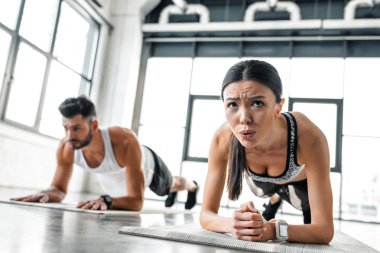 sportif kız ve erkek spor salonunda yoga paspaslar üzerinde tahta egzersiz yaparak yoğunlaştı 