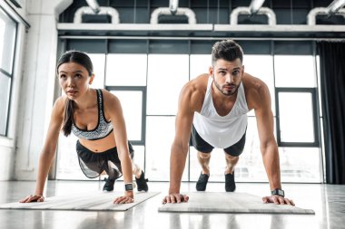 sportif genç çift itme yaparken konsantre ups spor salonunda yoga paspaslar