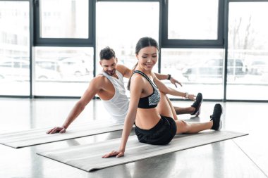 yoga paspaslar üzerine oturan ve spor salonunda germe mutlu genç çift