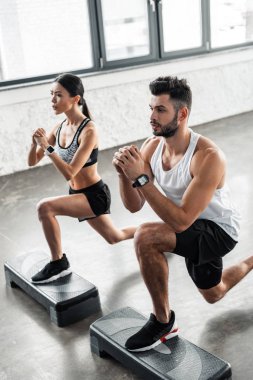yüksek açılı görünüş konsantre genç çiftin adım platformlarda egzersiz ve spor salonunda uzağa arıyorsunuz