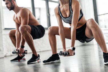 atış sportif genç erkek ve kadın spor salonunda dumbbells ile çömelme kırpılmış