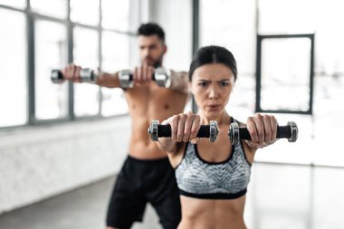 sportif genç çift eğitim salonunda dumbbells ile seçici odak