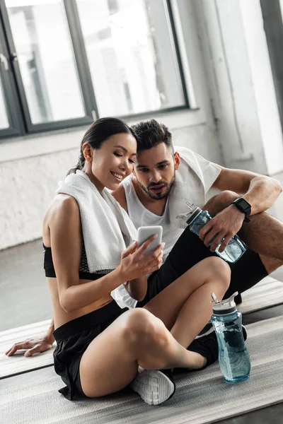 Smiling Sporty Couple Sitting Yoga Mats Using Smartphone Together Gym — Stock Photo, Image