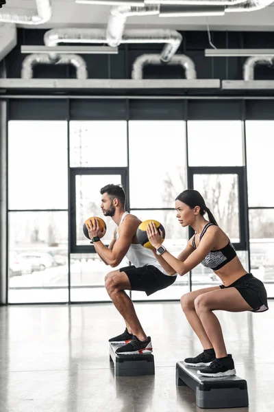 运动年轻夫妇在运动服装训练与阶梯平台在健身房的侧视图 — 图库照片