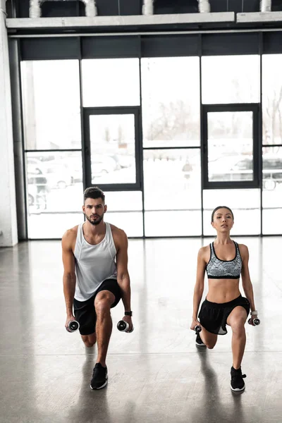 运动年轻夫妇在运动服装运动与哑铃在健身房的全貌 — 图库照片