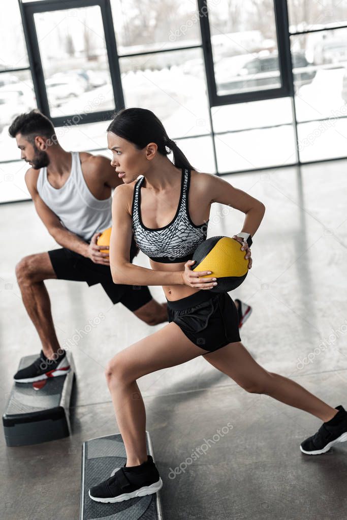 athletic young couple in sportswear training with step platforms in gym